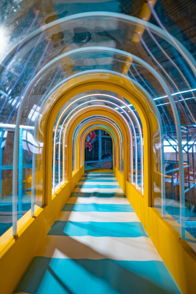 Gelber Krabbeltunnel mit transparenten Bögen im Spielturm